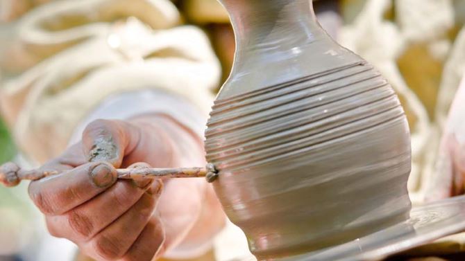 potter inflicts a decorative pattern on spinning pot